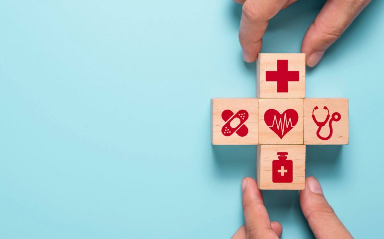hand-putting-wooden-cubes-healthcare-medicine-hospital-icon-blue-table-health-care-insurance-business-investment